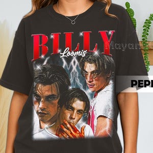Może przedstawiać: Czarna koszulka z grafiką trzech wizerunków mężczyzny z napisem "BILLY LOOMIS" w czerwonych literach. Projekt zawiera błyskawice i styl vintage.