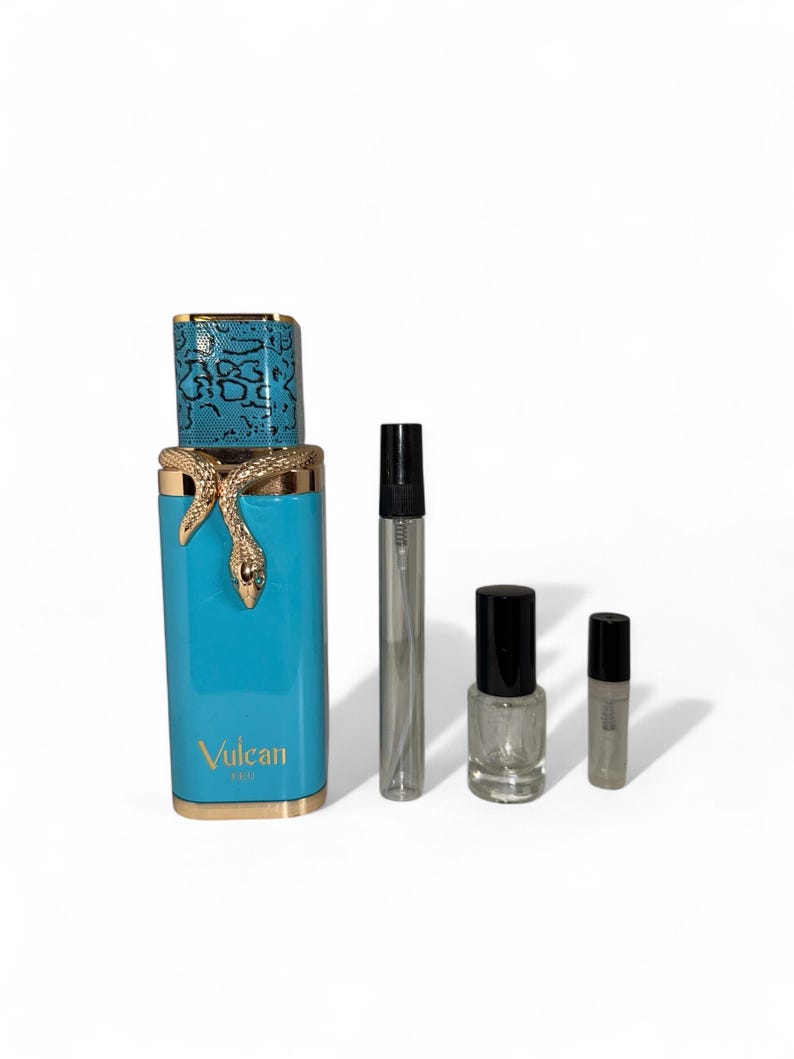 May include: A turquoise perfume bottle with a gold snake design and a blue snakeskin cap. The bottle is labeled "Vulcan". Also shown are a silver atomizer, a bottle of clear nail polish, and a small perfume sample.