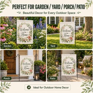 May include: A rectangular garden flag featuring a white background with a central floral wreath made of green leaves and pink and white flowers. The text "Welcome to Our Home" is printed in black script in the center of the wreath. The flag is displayed on a black metal stand.