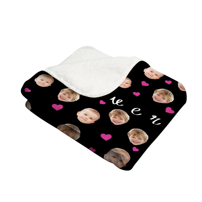 May include: A black fleece blanket with a repeating pattern of pink hearts and faces of children. The text "we are" is printed in white on the blanket.