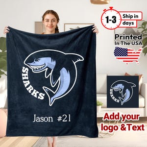 May include: A navy blue fleece blanket with a white shark graphic and the word "SHARKS" in a white circle. The text "Jason #21" is printed below the shark.