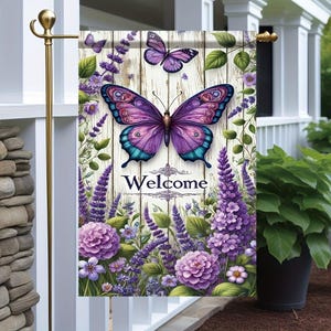 May include: A decorative garden flag featuring a large purple butterfly with teal accents, set against a backdrop of lavender flowers and a wooden plank design. The word "Welcome" is displayed in elegant script.
