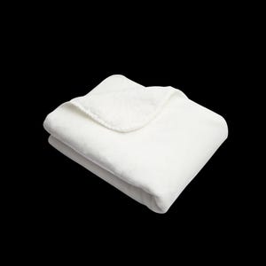 May include: A white plush blanket folded in half, showing the soft texture of the fabric.