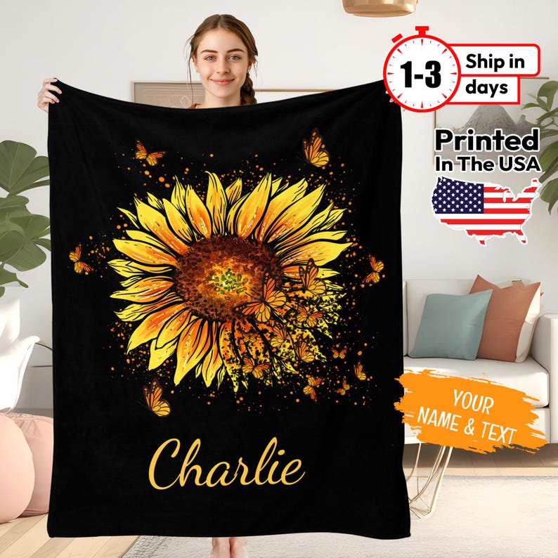 May include: Black fleece blanket featuring a large yellow sunflower with butterflies flying around it. The text "Charlie" is printed below the sunflower.