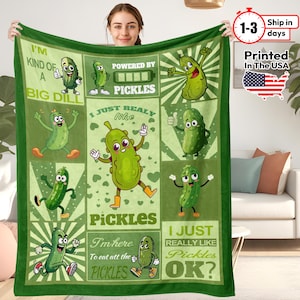 May include: Green blanket with cartoon pickle illustrations and text. The blanket features various pickle characters with phrases like "I'm kind of a big dill" and "Powered by Pickles." The blanket is printed in the USA.