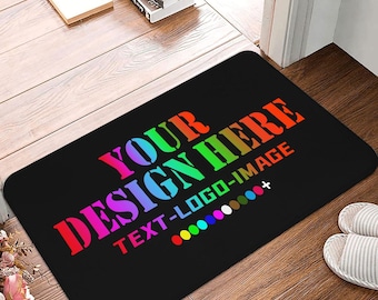 May include: Black rectangular doormat with the text "YOUR DESIGN HERE TEXT-LOGO-IMAGE" in a rainbow gradient. A color palette is displayed below the text. The mat is on a wooden floor, with a pair of slippers visible.