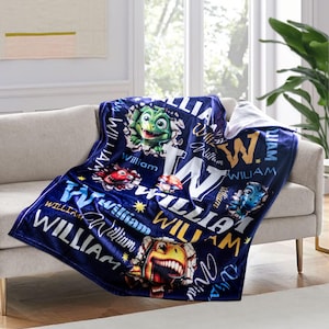 May include: A blue fleece blanket with a personalized name "William" printed in yellow and white. The blanket features a variety of colorful cartoon dinosaurs and stars.