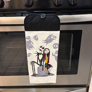 Puede incluir: Un pa&ntilde;o de cocina blanco con Jack Skellington y Sally de Pesadilla antes de Navidad, con dise&ntilde;os de fantasmas y calaveras grises. La parte superior es negra con un patr&oacute;n acolchado y un bot&oacute;n para colgar.