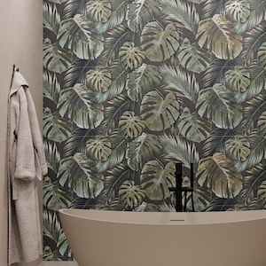 May include: A bathroom featuring a beige bathtub and a wall adorned with a dark background and a pattern of green and tan tropical leaves. A grey robe hangs on the wall to the left.
