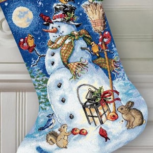 May include: A blue and white Christmas stocking with a snowman and a lantern. The stocking has the name "BRANDON" embroidered on it.