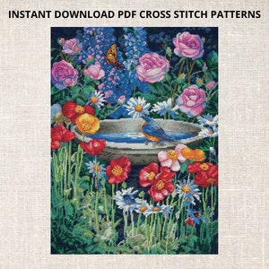 Op de afbeelding: Een kruissteekpatroon met een vogelbad omringd door kleurrijke bloemen, waaronder roze rozen, blauwe riddersporen en rode klaprozen. Een blauwe vogel zit op de rand van het bad, en een vlinder vliegt in de buurt.