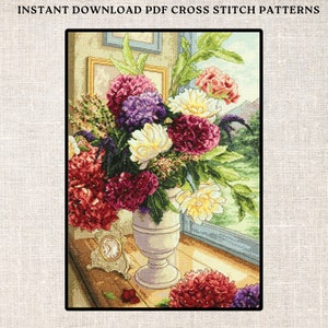 May include: A cross stitch pattern featuring a vase of colorful flowers in front of a window. The flowers are red, white, purple, and green. The vase is white and has a classic design. The window is blue and has a view of a green landscape.