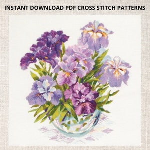 May include: A cross stitch pattern featuring a bouquet of purple and white irises in a clear glass vase. The flowers are arranged in a vase on a white background.