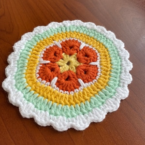 May include: A crocheted coaster with a white border, green, yellow, and orange concentric circles, and a flower design in the centre.