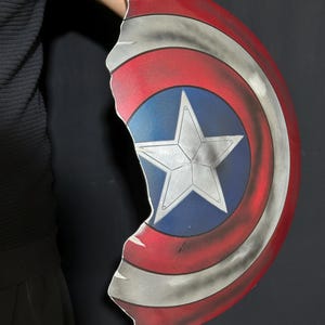 Op de afbeelding: Een beschadigd Captain America schild. Het schild is voornamelijk rood, wit en blauw, met een centrale witte ster op een blauwe achtergrond. Het schild heeft een gehavende uitstraling met een gekartelde rand.