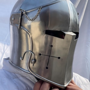 Peut inclure: Casque de chevalier m&eacute;di&eacute;val argent&eacute; et poli. Le casque pr&eacute;sente une croix sur la plaque frontale, une cha&icirc;ne et une pi&egrave;ce m&eacute;tallique incurv&eacute;e. Le casque est con&ccedil;u pour prot&eacute;ger la t&ecirc;te et le visage.