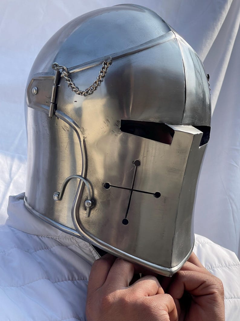 Peut inclure: Casque de chevalier m&eacute;di&eacute;val argent&eacute; et poli. Le casque pr&eacute;sente une croix sur la plaque frontale, une cha&icirc;ne et une pi&egrave;ce m&eacute;tallique incurv&eacute;e. Le casque est con&ccedil;u pour prot&eacute;ger la t&ecirc;te et le visage.