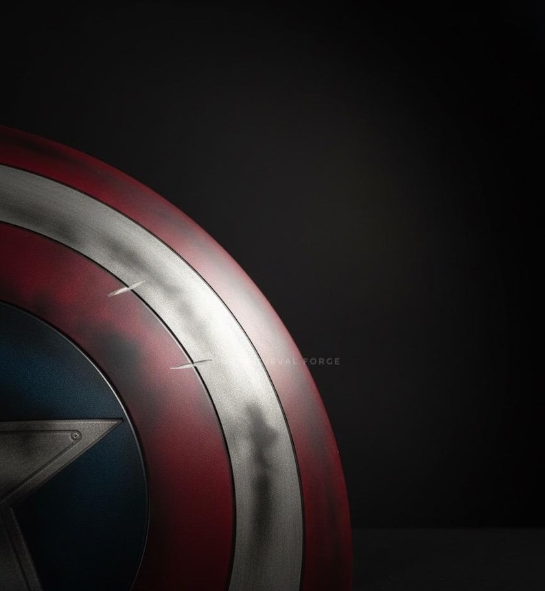 May include: A close-up of a Captain America shield. The shield features a red and white striped design with a silver band and a blue circle with a star in the center. The shield has a distressed, battle-worn appearance.