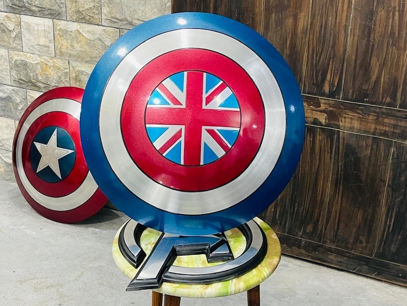 May include: Two round shields with a blue, red, and silver color scheme. One shield features a white star on a red background, while the other has a Union Jack design. The shields are props, possibly for cosplay or display.