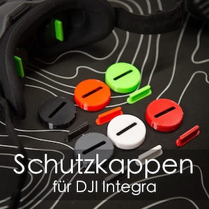 Könnte beinhalten: Ein Satz bunter Schutzkappen für DJI Integra Drohnenpropeller. Die Kappen sind schwarz, weiß, rot, grün und orange. Die Kappen sind so konzipiert, dass sie die Propeller vor Beschädigungen schützen.