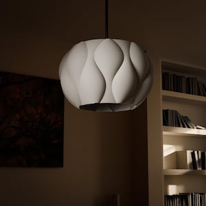 May include: A white, round pendant light fixture with a wavy, textured surface. The light is hanging from a black cord.