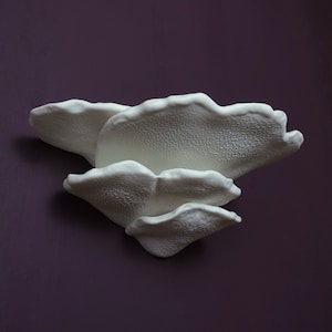 May include: Three white ceramic wall sculptures shaped like mushrooms, stacked on top of each other.