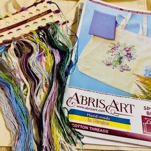 May include: A cross-stitch shopper kit with colorful cotton threads. The kit includes a tote bag, a pattern, and a variety of embroidery floss in shades of blue, green, purple, and yellow. The kit is hand-made in Ukraine.