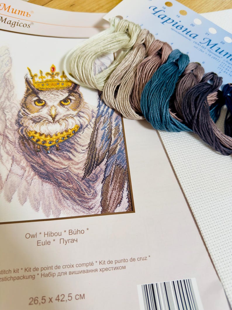 Puede incluir: Un kit de punto de cruz con un dise&ntilde;o de b&uacute;ho coronado. Incluye hilos de bordar de varios colores y tela blanca. El embalaje muestra el texto "Owl * Hibou * B&uacute;ho * Eule * Пугач" y mide 26,5 x 42,5 cm.