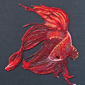 Peut inclure: Un poisson combattant rouge en perles avec des nageoires flottantes, créé à l'aide d'une aiguille et d'un fil. Le poisson est représenté dans une couleur rouge vibrante avec une bouche rose et un œil noir.