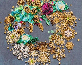 May include: A decorative wreath composed of gold-toned snowflake ornaments, vibrant green and blue beaded floral accents, and small colourful crystals on a dark grey fabric background. The text MERRY CHRISTMAS is printed in gold at the bottom.