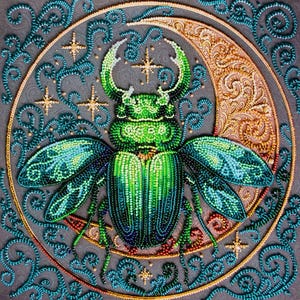 May include: A detailed, beaded artwork featuring a green and blue beetle with large horns, set against a grey background. The beetle is surrounded by a gold crescent moon and teal swirls, with gold star accents. The artwork is square in shape.
