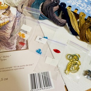 Puede incluir: Un kit de punto de cruz con un dise&ntilde;o de b&uacute;ho, que incluye hilos de bordar de varios colores, cuentas y un adorno dorado. El kit incluye un patr&oacute;n impreso, tela Aida y una etiqueta con c&oacute;digo de barras.