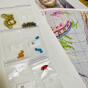 Cross stitch kit contents including Aida fabric, Madeira floss, Czech beads, needles and printed chart.