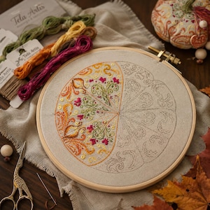 Embroidery work in progress shown in an embroidery hoop. The pumpkin pincushion design features counted cross stitch, decorative stitches, autumn-inspired motifs, and hand-dyed thread colors. This photo demonstrates the stitching process and detail of the sampler before final assembly.