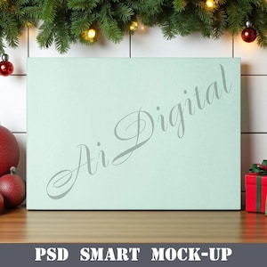 May include: A light green rectangular box with the text "Ai Digital" in a cursive font. The box is on a wooden surface, decorated with Christmas ornaments and greenery. The text "PSD SMART MOCK-UP" is at the bottom.