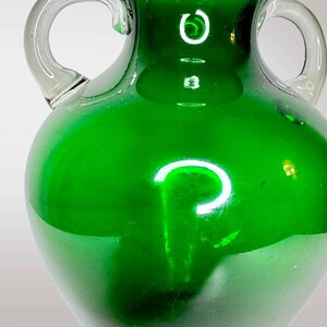 May include: A green glass vase with two handles. The vase has a rounded body and a smooth, glossy finish.