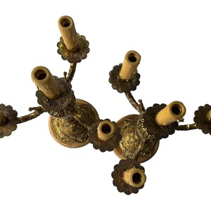 Pu&ograve; includere: Un candelabro vintage in ottone con sette portacandele. Il candelabro presenta un design floreale attorno alla base e ai portacandele. I portacandele sono disposti a cerchio. Un oggetto decorativo per la casa.