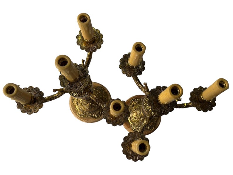 Pu&ograve; includere: Un candelabro vintage in ottone con sette portacandele. Il candelabro presenta un design floreale attorno alla base e ai portacandele. I portacandele sono disposti a cerchio. Un oggetto decorativo per la casa.