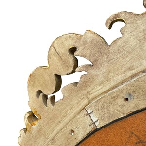 May include: Close-up of a section of a vintage, ornate, gold-painted wooden frame. The frame has a detailed, scrolled design with visible wear and tear, revealing the wood beneath the paint. The background is white.