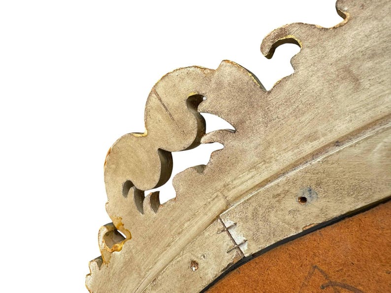 May include: Close-up of a section of a vintage, ornate, gold-painted wooden frame. The frame has a detailed, scrolled design with visible wear and tear, revealing the wood beneath the paint. The background is white.