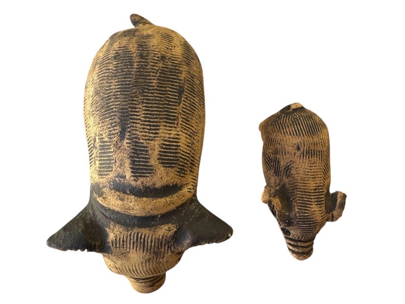 Pu&ograve; includere: Due sculture in ceramica marrone e nera. La scultura pi&ugrave; grande ha una forma a testa con una base larga e una piccola pinna sulla parte superiore. La scultura pi&ugrave; piccola ha un design simile, ma &egrave; pi&ugrave; piccola e pi&ugrave; arrotondata.
