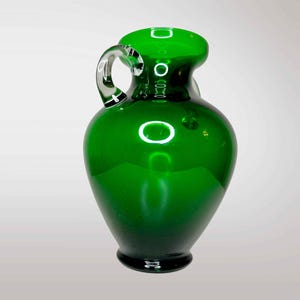 May include: A dark green glass vase with a clear glass handle. The vase has a rounded body and a narrow neck.