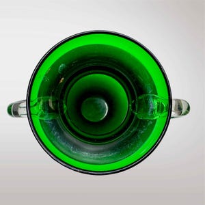 May include: A green glass vase with two handles. The vase is empty and has a smooth, shiny surface.