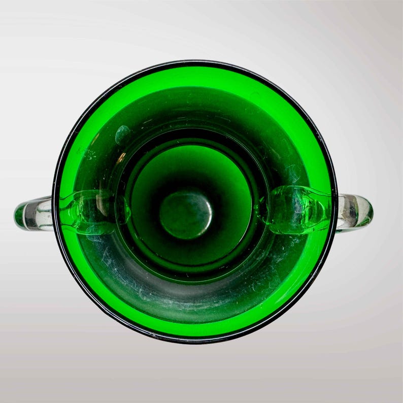 May include: A green glass vase with two handles. The vase is empty and has a smooth, shiny surface.