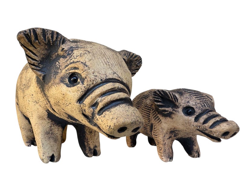 Pu&ograve; includere: Due statuette di maiale in ceramica. Il maiale pi&ugrave; grande &egrave; marrone chiaro con accenti marrone scuro, e il pi&ugrave; piccolo ha una colorazione simile. Entrambi hanno dettagli, tra cui orecchie, musi e occhi. Sono oggetti decorativi.