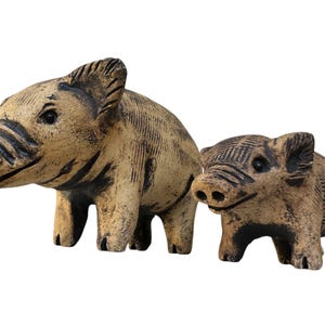 Pu&ograve; includere: Due statuette di cinghiali in ceramica. Il cinghiale pi&ugrave; grande &egrave; beige con strisce e dettagli marrone scuro. Il cinghiale pi&ugrave; piccolo ha una colorazione e dettagli simili.