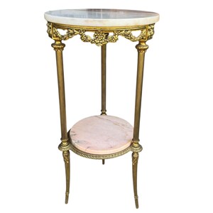May include: An antique, two-tiered side table with a marble top and a lower shelf. The table has a gold-coloured metal frame with ornate floral detailing and slender legs. The top is approximately 61 cm in diameter.