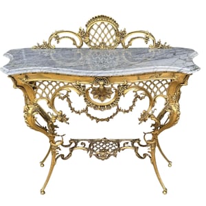 May include: Ornate gold-colored console table with a gray marble top. The table features intricate scrollwork, lattice patterns, and floral motifs. The legs are slender and curved, adding to the table's elegant design.