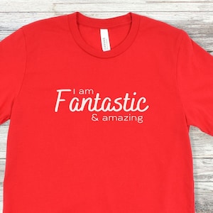May include: Red t-shirt with white text that reads "I am Fantastic & amazing".