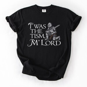 May include: Black t-shirt with a white graphic of a knight kneeling with a sword and the text "Twas the tism, M'Lord".